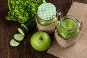 Refreshing green smoothie made with apple, cucumber, and lettuce served in mason jars on wooden background.